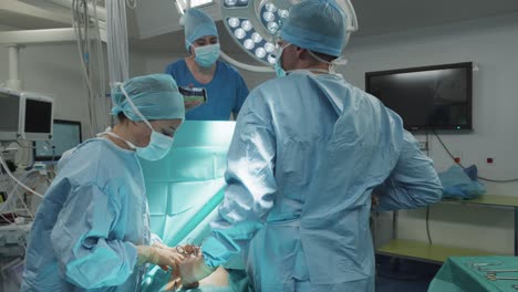 Slow-motion-rotating-shot-showing-surgeons-and-nurses-operating-on-a-patient-in-theatre