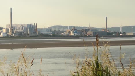 Looking-across-river-Mersey-estuary-to-Runcorn-industrial-waterfront-factory-businesses-at-sunrise-low-tide