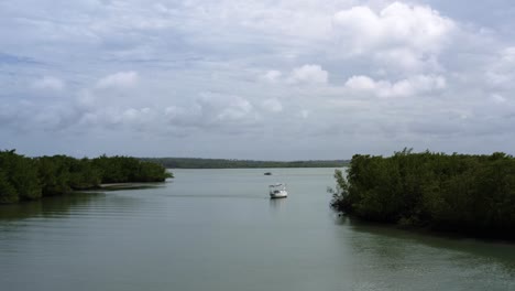 Aerial-drone-shot-of-an-abandoned-sail-boat-anchored-in-the-tropical-Guaraíras-Lagoon-surrounded-by-mangrove-forests-near-Tibau-do-Sul,-Brazil-in-Rio-Grande-do-Norte-on-a-warm-sunny-summer-day