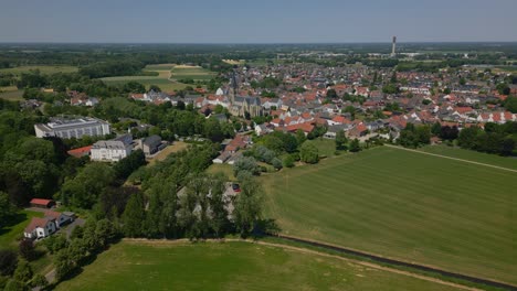 Luftdrohnenaufnahme-Der-Idyllischen-Gemeinde-Thorn,-Maasgouw-In-Limburg-Mit-Blick-Auf-Die-Schöne-Grüne-Und-Flache-Landschaft,-Die-Häuser-In-Niederländischer-Architektur-Und-Den-Kirchturm-An-Einem-Sonnigen-Tag