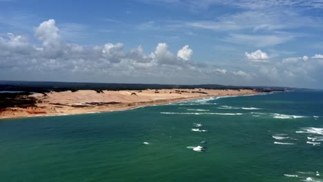 Dolly-in-aerial-drone-shot-of-the-Malembá-crossing-where-the-atlantic-ocean-joins-with-the-Guaraíras-lagoon-with-large-sand-dunes-in-Tibau-do-Sul-near-Pipa,-Brazil-in-Rio-Grande-do-Norte-on-summer-day