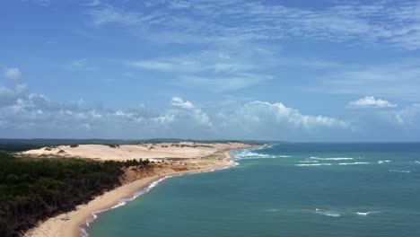 Left-trucking-aerial-drone-shot-of-the-stunning-tropical-Malembá-beach-sand-dunes-near-Tibau-do-Sul-in-Rio-Grande-do-Norte,-Brazil-with-a-sand-buggy-approaching-on-a-warm-sunny-summer-day