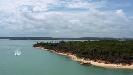 Aufsteigende-Luftdrohnenaufnahme-Des-Tropischen-Muquiço-Strandes-Mit-Goldenem-Sand-Und-Exotischem-Dschungel-An-Der-Guaraíras-Lagune-Mit-Angedockten-Und-Segelnden-Fähren-In-Der-Nähe-Von-Tibau-Do-Sul,-Brasilien-In-Rio-Grande-Do-Norte
