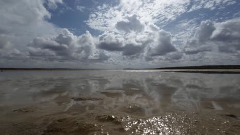 Beautiful-trucking-right-landscape-worms-eye-view-shot-of-a-tropical-wet-sand-bar-in-the-Guaraíras-Lagoon-of-Tibau-do-Sul,-Brazil-in-Rio-Grande-do-Norte-during-a-sunny-summer-cloudy-day-near-Pipa