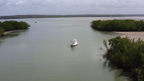 Dolly-in-aerial-drone-shot-of-an-abandoned-sail-boat-anchored-in-the-tropical-Guaraíras-Lagoon-surrounded-by-mangrove-forests-near-Tibau-do-Sul-Brazil-in-Rio-Grande-do-Norte-on-a-warm-sunny-summer-day