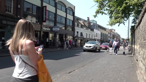 People-walk-along-Regent-Street-on-a-sunny-day-in-Cambridge,-UK