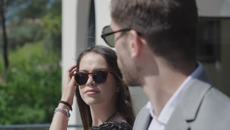 Slow-motion-shot-of-a-couple-wearing-sunglasses-looking-towards-each-other-in-the-wind