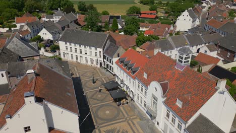 Descending-drone-shot-of-historic-buildings-in-the-heart-of-Thorn,-Maasgouw,-Limburg-in-the-netherlands-with-dutch-architecture-and-flat-landscape