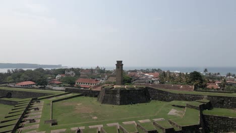 Aerial-rises-over-clock-tower-and-medieval-fort-in-Galle,-Sri-Lanka