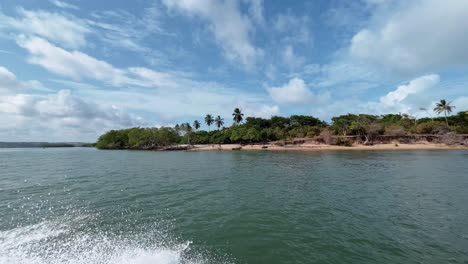 Rotating-shot-quickly-passing-by-the-tropical-secluded-Muquiço-Beach-from-the-POV-of-a-boat-on-the-Guaraíras-lagoon-in-Tibau-do-Sul,-Brazil-in-Rio-Grande-do-Norte-during-a-warm-sunny-summer-day