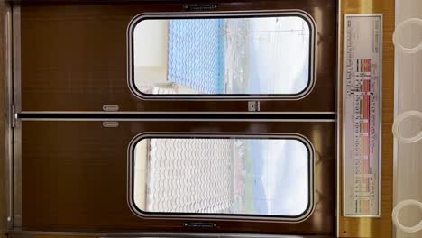 Interior-of-Kyoto-subway-with-suburbs-view-through-door-window,-motion-vertical-view