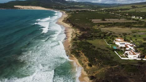 Expensive-villas-on-sandy-foamy-ocean-coastline,-aerial-view