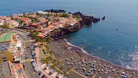 Aerial-view-of-crowded-La-Arena-beach,-Tenerife,-with-black-volcanic-sand