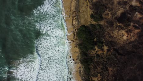 Massive-white-foamy-waves-crashing-on-Spain-coastline,-top-down-view