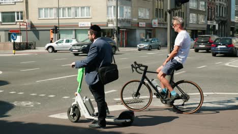 Hombre-Judío-Con-Sombrero-Kipá-En-Scooter-Eléctrico-Esperando-En-El-Cruce-En-El-Distrito-De-Los-Diamantes-De-Amberes,-Bélgica