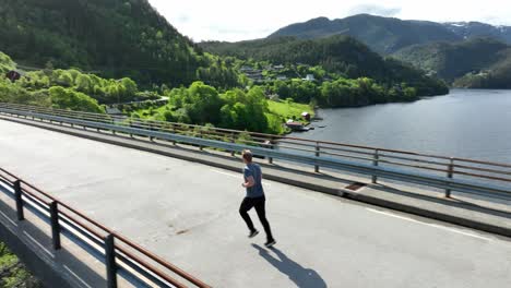 Hombre-Corriendo-Sobre-El-Puente-De-Noruega-Occidental-Con-El-Pintoresco-Fiordo-Veafjorden-En-Segundo-Plano.