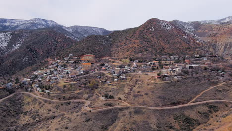Jerome-old-mountainside-mining-town,-Arizona-establishing-aerial-view-rising-away-to-reveal-valley-landscape