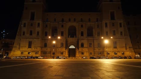 Palazzo-Del-Governo-Gebäude-In-Taranto,-Italien,-An-Der-Piazetta-Gandhi-Straße-Bei-Nacht-Mit-Vertikaler-Schwenkung