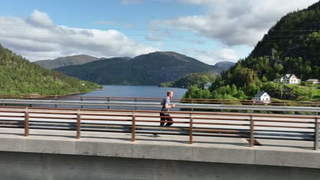 Aerial-tracking-following-man-jogging-over-bridge-in-Western-Norway