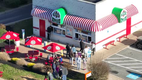 People-standing-and-sitting-at-Rita's-ice-restaurant,-Pennsylvania,-USA