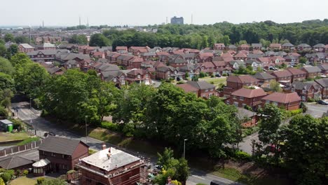 Builders-working-on-modern-red-brick-house-rooftop-renovation-aerial-view-panning-across-suburban-townhouse-development