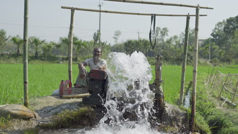 Bangladeschischer-Bauer-Besucht-Eine-Wasserpumpe,-Die-Das-Grüne-Reisfeld-Mit-Wasser-Versorgt-–-Landwirtschaftliches-Wachstum-In-Bangladesch,-4K-HD-422-10-Bit-Filmmaterial