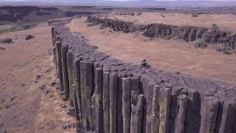 Aerial-pan:-Hiker-walks-on-tops-of-rock-columns,-Washington-Scablands