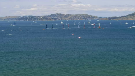 Aerial-view-panning-across-San-Francisco-sailing-grand-prix-as-many-boats-navigate-at-speed-under-mountain-landscape