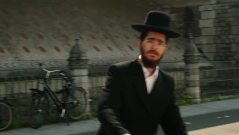 Young-Jewish-man-biking-in-the-Antwerp-Diamond-district,-Belgium---Close-up