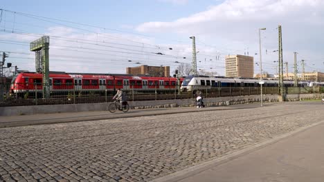 Los-Trenes-Regionales-Pasan-Entre-Sí-Al-Lado-Del-Pavimento-Adoquinado-Junto-Al-Puente-Hohenzollern-En-Colonia