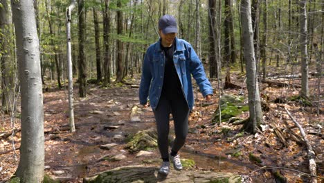 Young-woman-feeling-happy-successful-healthy-active-and-accomplished-appreciates-nature-outdoors-in-upstate-new-york-forest-on-cloudy-day-before-walking-by-camera