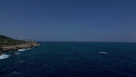 Motorboat-Across-The-Sea-Near-Rugged-Shore-Of-Il-Ġolf-l-Iswed-National-Park-In-Marsaskala,-Malta