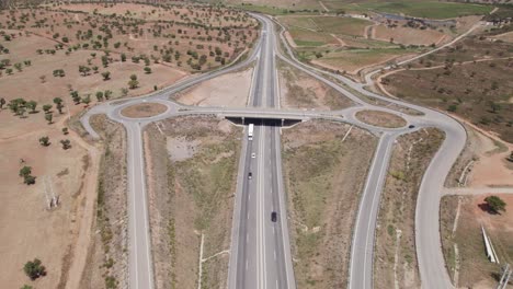 Aerial-pull-out-of-highway-with-exits-by-dry-landscape-in-Portugal