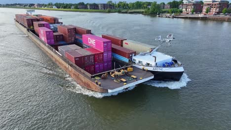 Panoramic-view-of-a-loaded-container-ship-sailing-through-River-Noord-at-sunset