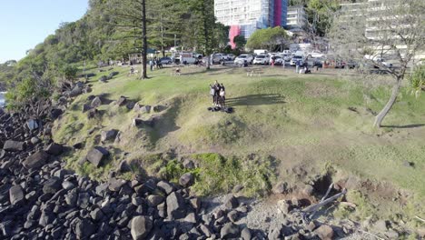 Group-Of-Friends-Waving-At-Drone-Camera-From-Burleigh-Hill-Picnic-Ground-In-Queensland,-Australia