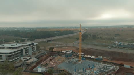 Drone-aerial-of-building-crane-at-an-office-block-building-site-rotating