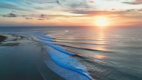 Panning-drone-shot-of-a-beautiful-golden-Indonesian-sunset,-at-the-internationally-renowned-surf-break-on-Grajagan-Bay,-Banyuwangi,-Java