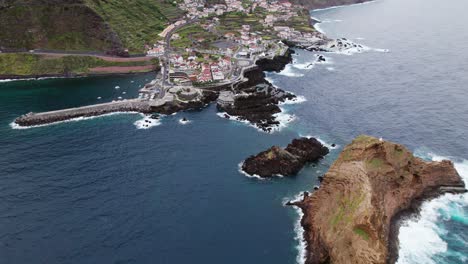 drone-view-Small-town-near-coast-in-Madeira,-rocky-cliffs,-cloudy-weather,-Portugal