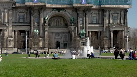 Gente-Disfrutando-Del-Sol-En-Lustgarten-Con-Fuente-Springbrunnen-Y-La-Catedral-De-Berlín-En-Segundo-Plano.