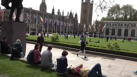 Tourists-relax-on-Parliament-Square-in-central-London,-UK