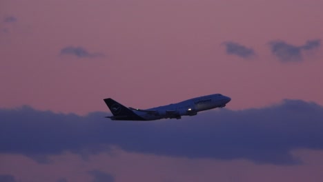 El-Avión-De-Pasajeros-De-Lufthansa-Despega-Mientras-El-Sol-Se-Pone-Creando-Un-Cielo-Parcialmente-Nublado-De-Color-Rosa-Y-Morado