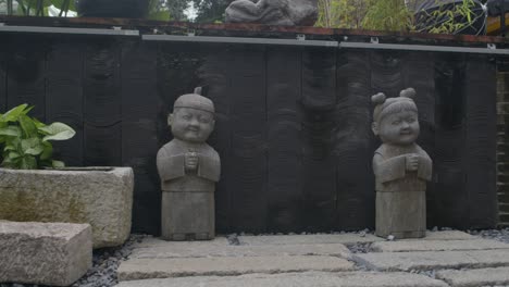Steingeschnitzte-Statuen-Süßer-Asiatischer-Jungen-Und-Mädchen-Im-Stilisierten-Asiatischen-Garten