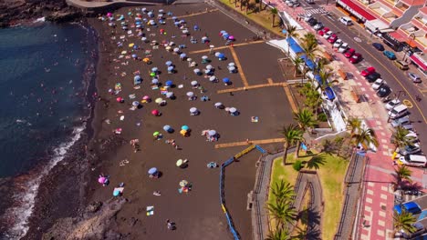 Luftaufnahme-Des-Belebten-Strandes-La-Arena,-Santiago-Del-Teide,-Mit-Sonnenschirmen