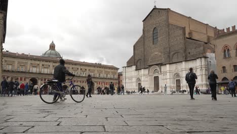 Touristen,-Die-Auf-Der-Piazza-Maggiore-Mit-Der-Basilika-San-Petronio-Im-Hintergrund-In-Bologna-Vorbeigehen