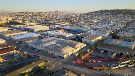 Serene-golden-hour-drone-shot-capturing-an-intersection-in-San-Francisco's-Bayview-neighborhood,-with-downtown-buildings-in-the-background