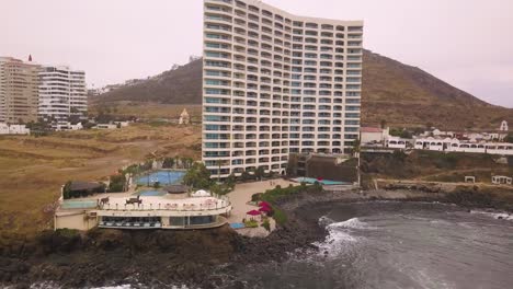 Shot-moving-away-from-a-grand-hotel-with-a-pool-on-the-shores-of-the-sea-in-Mexico