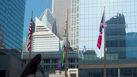 Chicago,-IL-USA-June-18th-2023:-the-American-flag-along-with-others-is-gently-blowing-in-the-wind-in-downtown-Chicago-next-to-the-modern-architecture