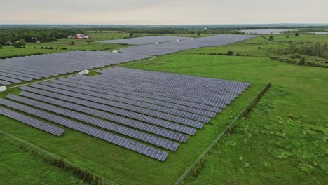 Rows-Of-Photovoltaic-Solar-Cells-In-Green-Field---aerial-drone-shot