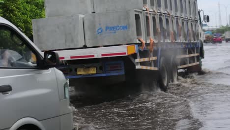 Truck-and-car-vehicles-pass-through-tidal-floods-in-the-city-of-Semarang,-Central-Java,-Indonesia