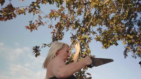Adult-female-using-a-saw-to-cut-overgrown-tree-branches-in-slow-motion
